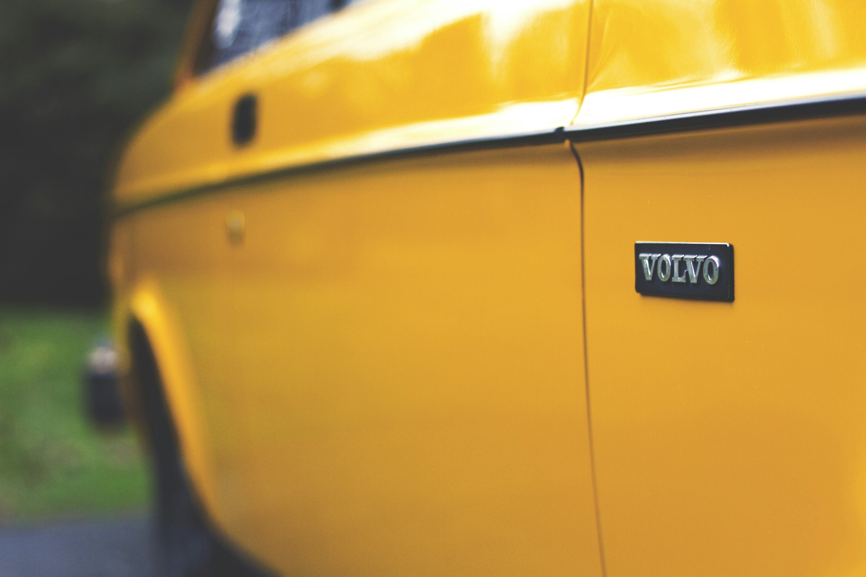 Close crop of the rear wing and chrome VOLVO badge of a yellow Volvo